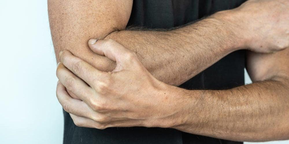 A man is holding his bent elbow because it is too painful to extend because of bursitis.