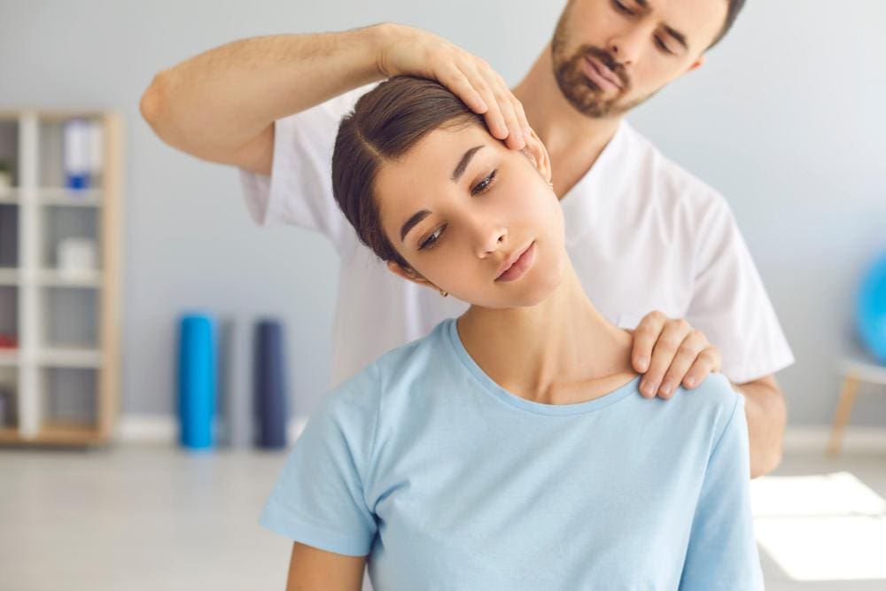 A woman is getting a chiropractic adjustment for a pinched nerve in her neck.