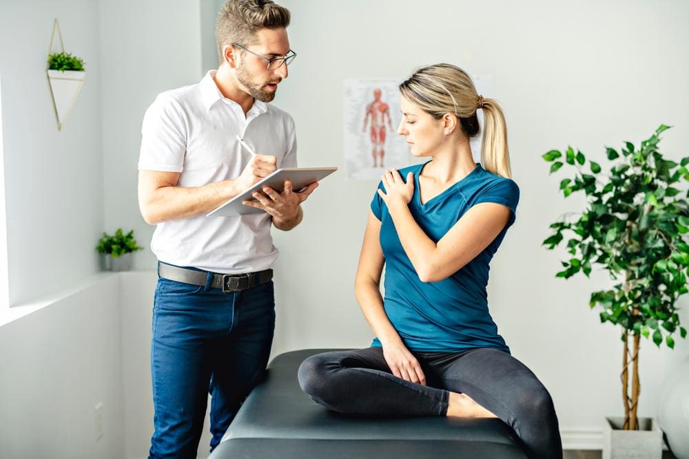 A chiropractor is discussing treatment options with a woman for her personal injuries. 