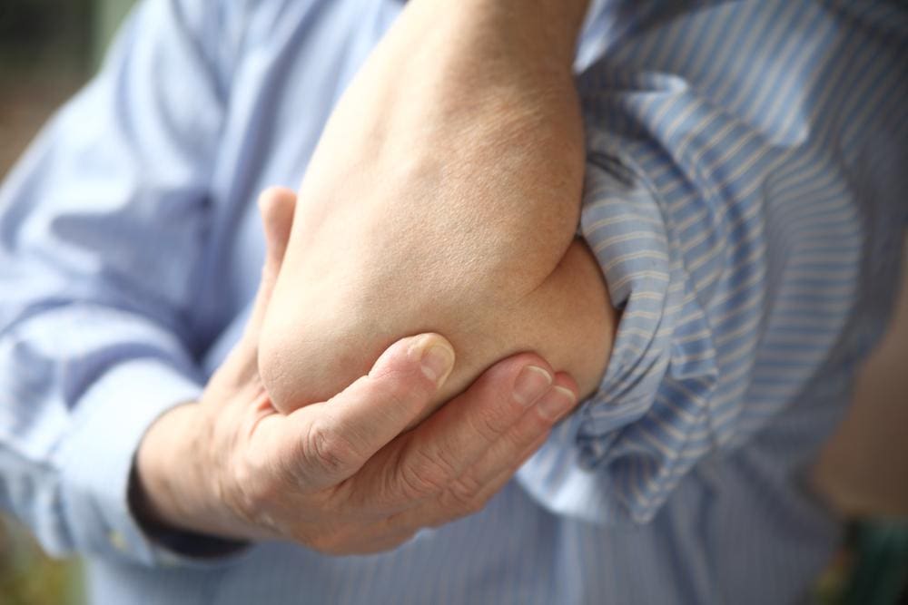 A man is holding his elbow because of pain from bursitis. 