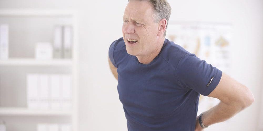 A man is in a lot of pain and cannot stand up straight because of a herniated disc.