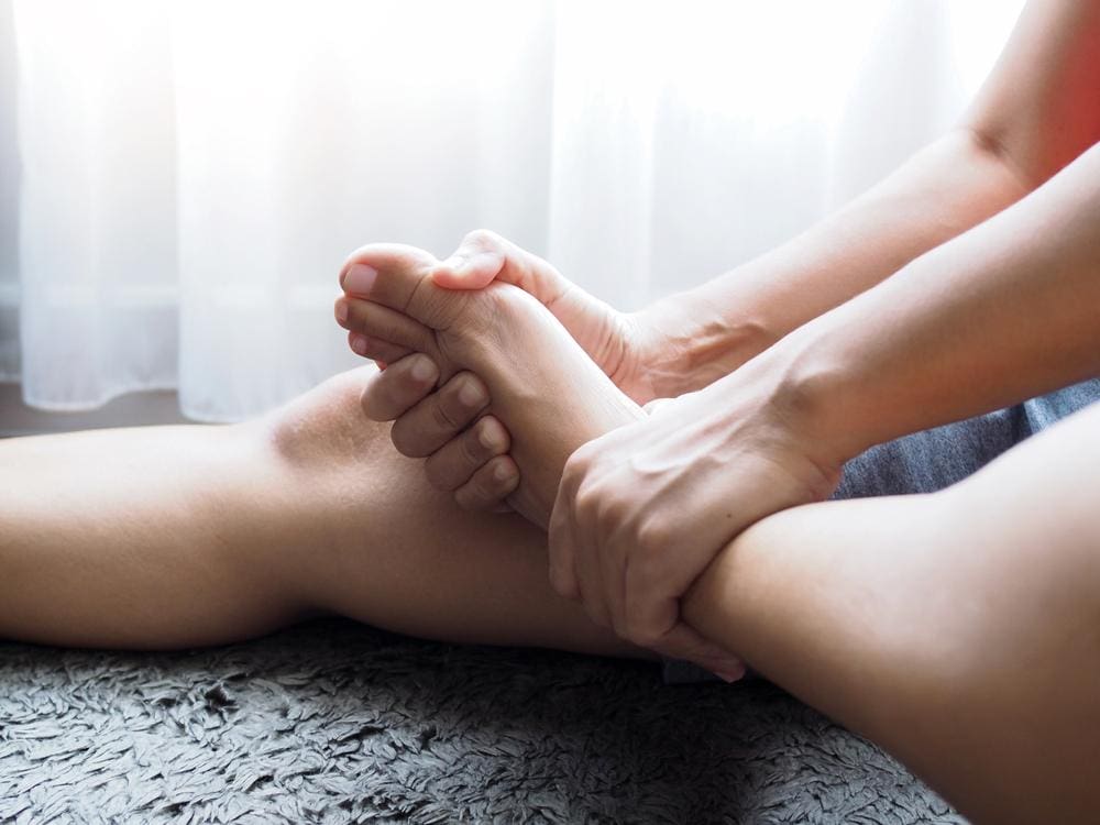 A person is holding their foot because of plantar fasciitis. 
