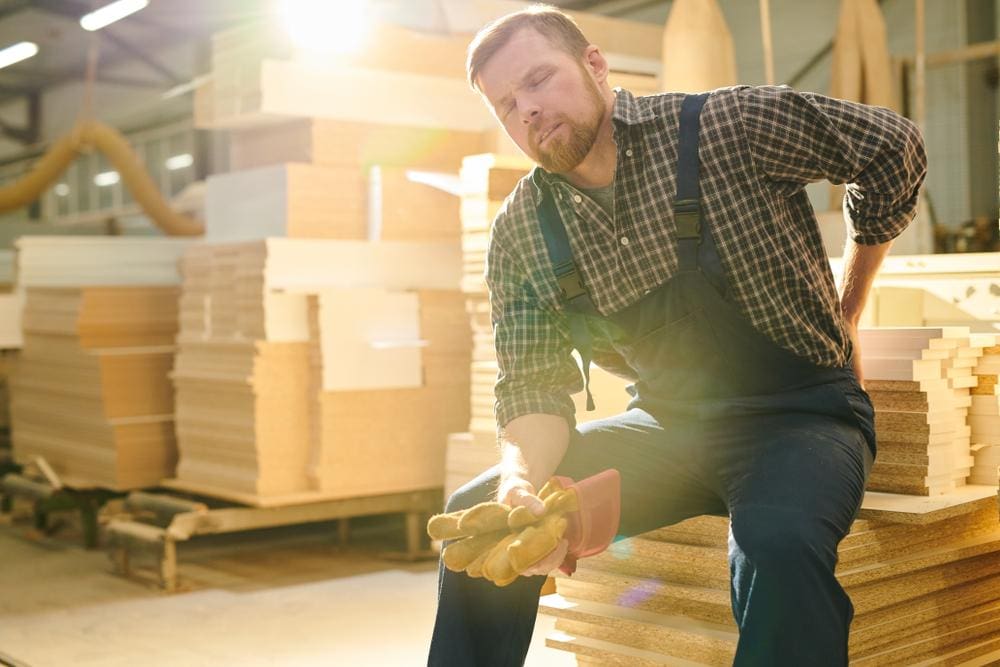 A man who works at a lumber yard is taking a break because he pulled a muscle in his back at work. 