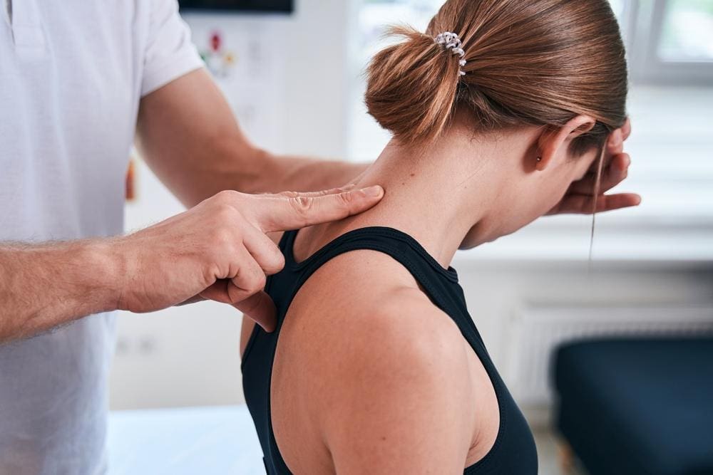 A woman is getting treated by a chiropractor for a pinched nerve in her spine. 