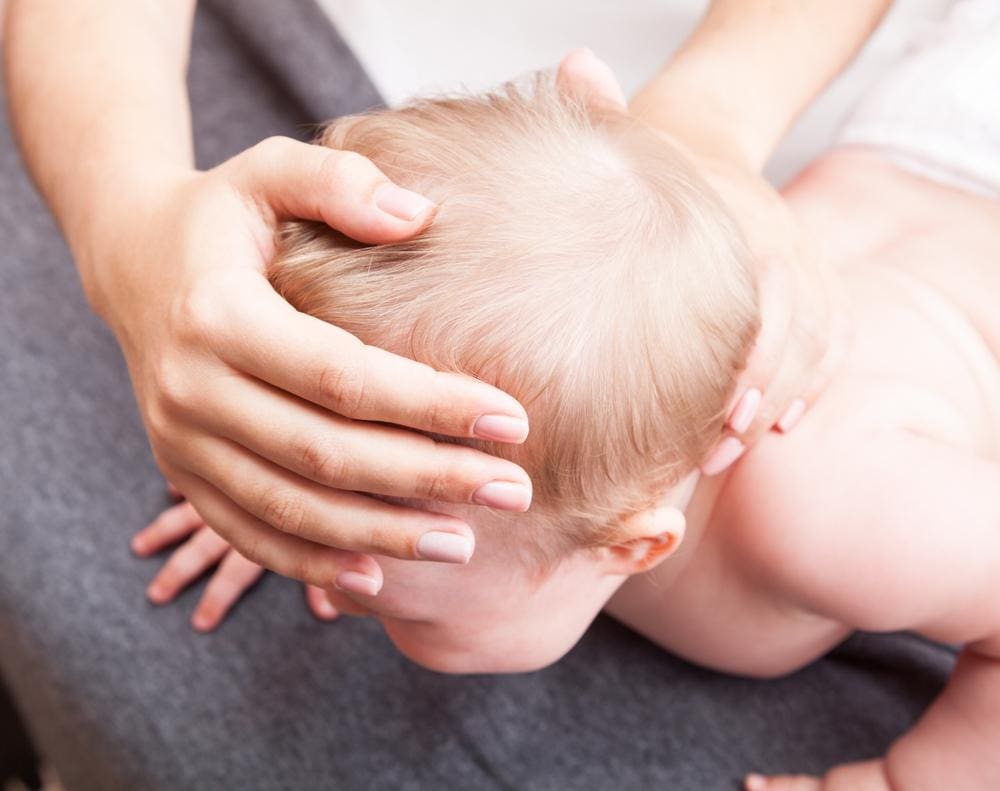 A chiropractor is performing an adjustment on a baby.

