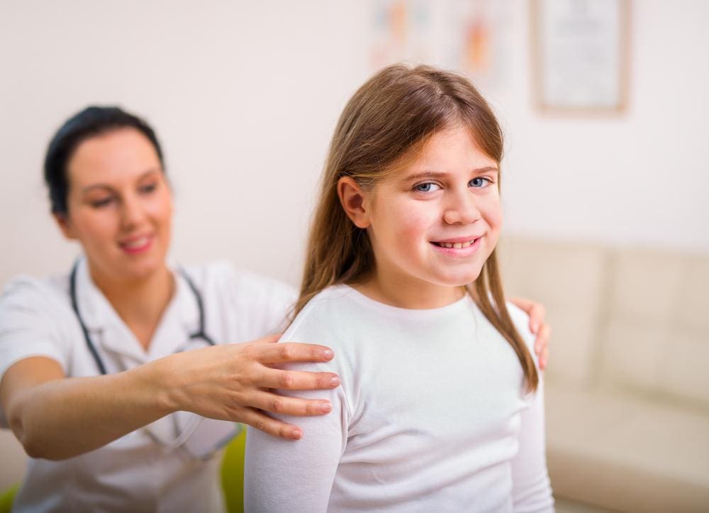 A child is smiling while visiting a chiropractor. 
