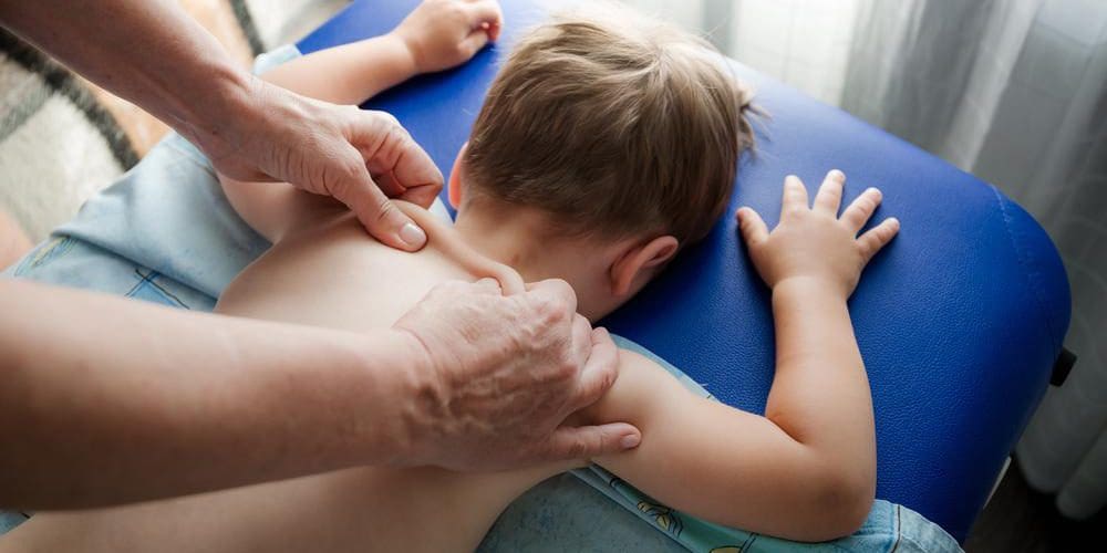 A child is getting a back adjustment form a chiropractor.