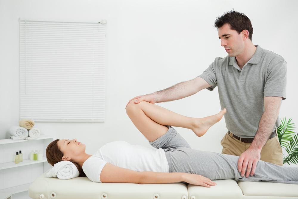 A chiropractor is treating a woman for a hamstring injury. 