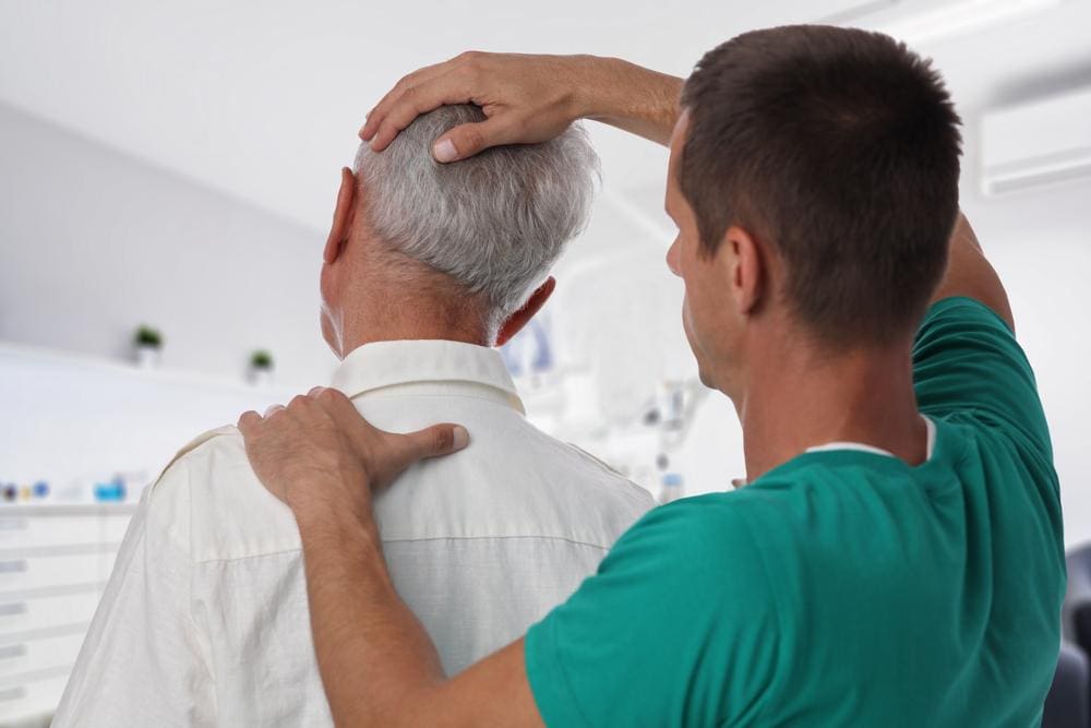 A chiropractor is administering a spinal adjustment to help relieve symptoms of sleep apnea.  