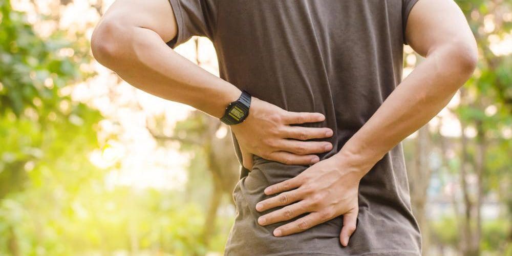 A man is holding his lower back because of chronic back pain.