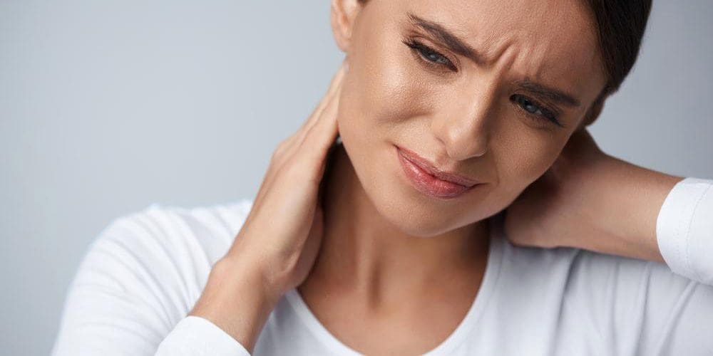 A woman is wincing because she suffers from chronic pain.
