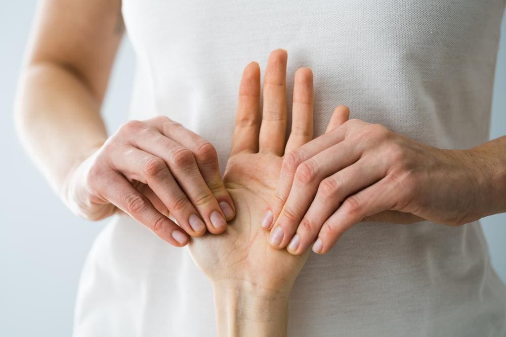 A chiropractor is treating a patient's hand for numbness. 