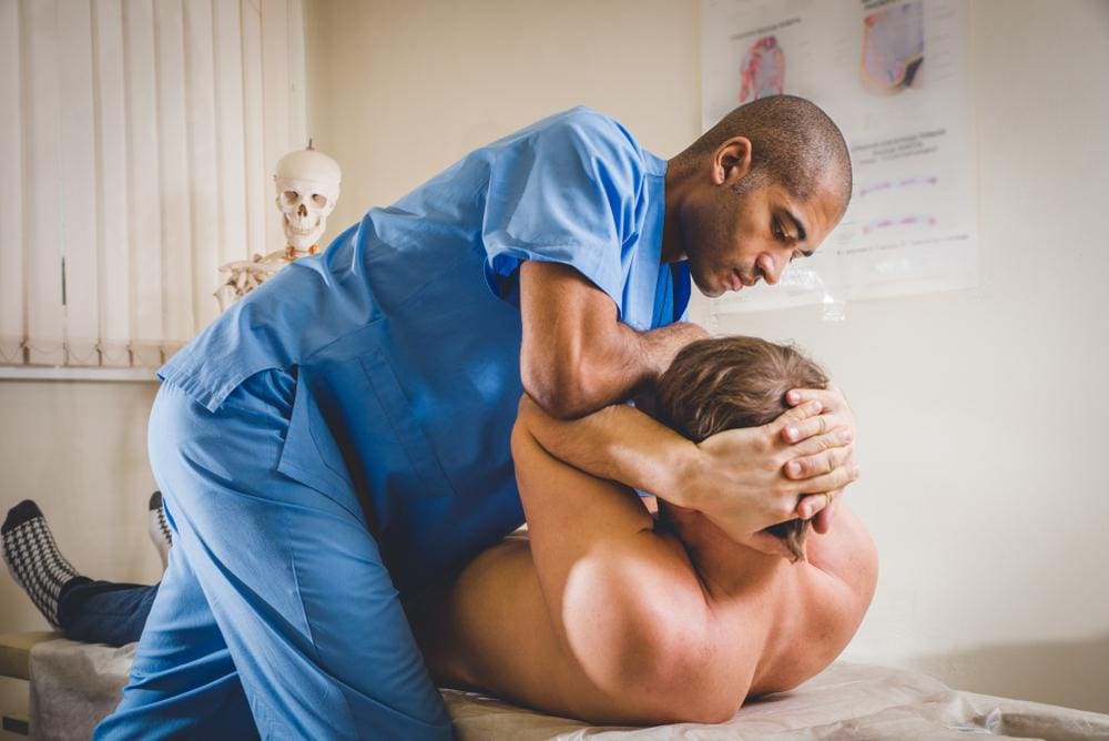 A chiropractor is treating a man with a herniated disc. 