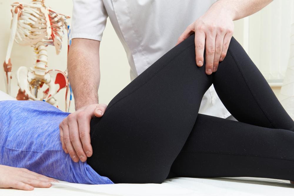 A chiropractor is treating a woman for hip flexor pain. 