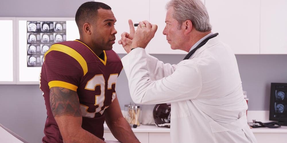 A doctor is testing a football player for concussion symptoms.