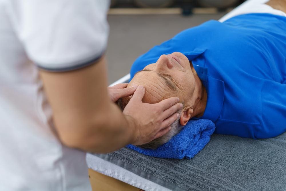 A chiropractor is treating a man for headaches. 