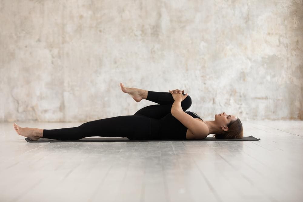 A woman is lying on her back, doing streatching exercises to ease herniated disc pain.