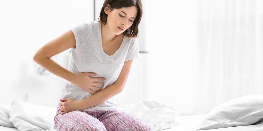 A woman is clutching her abdomen because of abdominal pain.