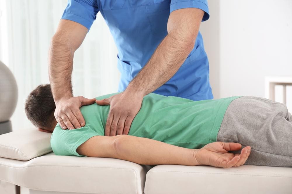 A teen boy is getting a chiropractic adjustment. 