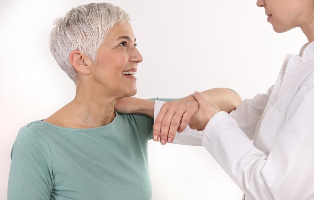 A chiropractor treating a woman for arthritis and reliving her pain. 