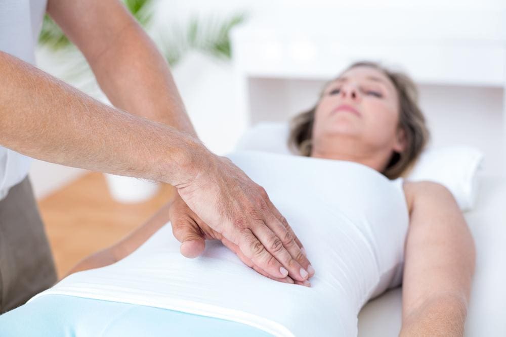 A chiropractor is treating a woman for stomach pain. 