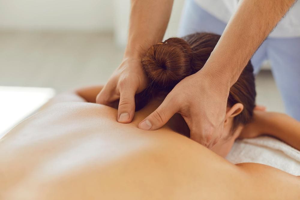 A chiropractor is administering therapeutic massage to alleviate trigeminal nerve pain.
