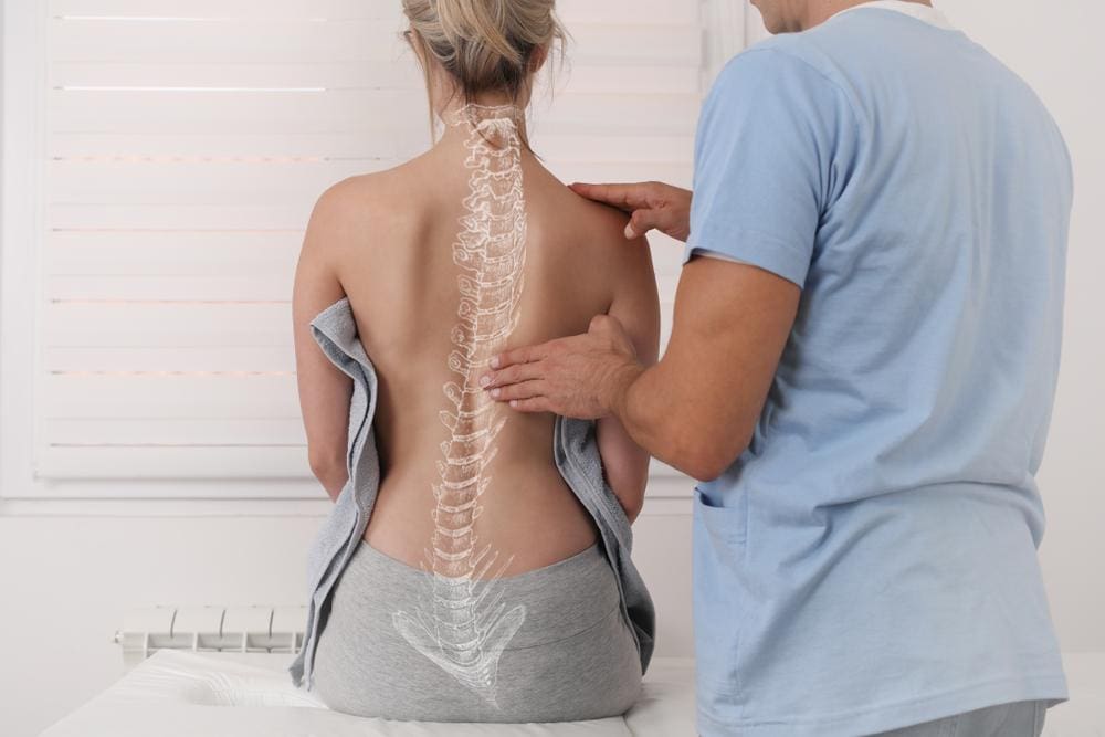 A chiropractor is examining a woman's spinal alignment. 