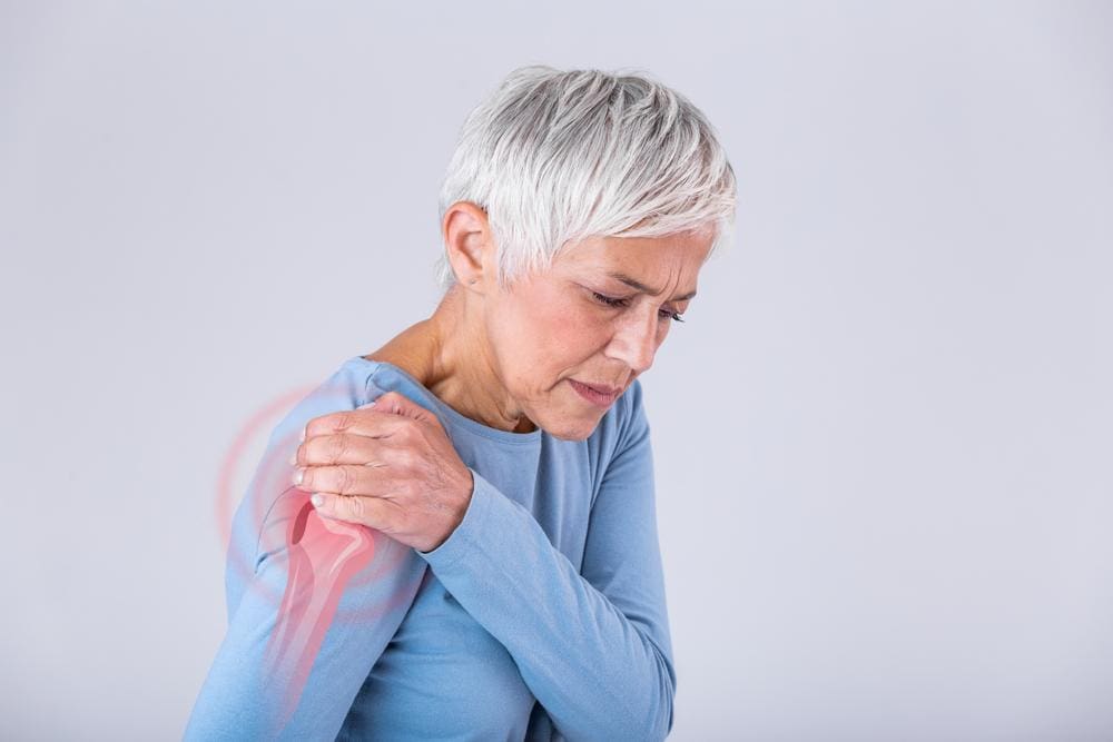 A woman is clutching her shoulder because shoulder pain is impeding mobility. 