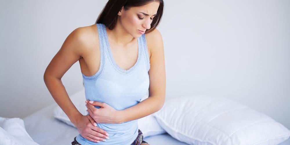 A woman is suffering because of abdominal pain.