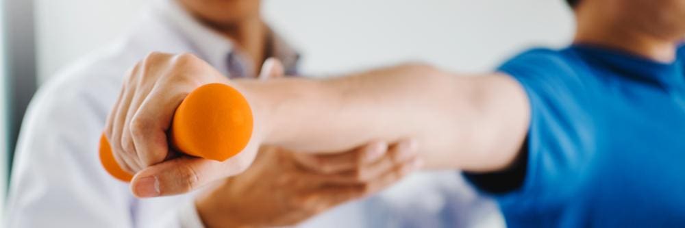 A man is doing physical therapy exercises for shoulder injury recovery. 