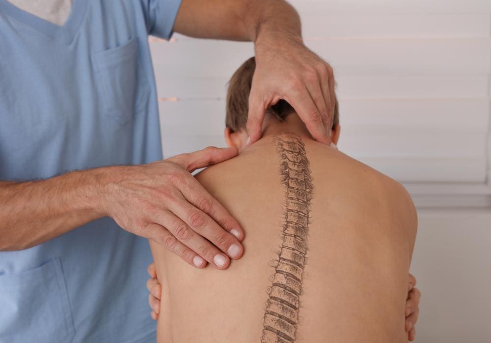 A chiropractor is treating a kid for scoliosis. 
