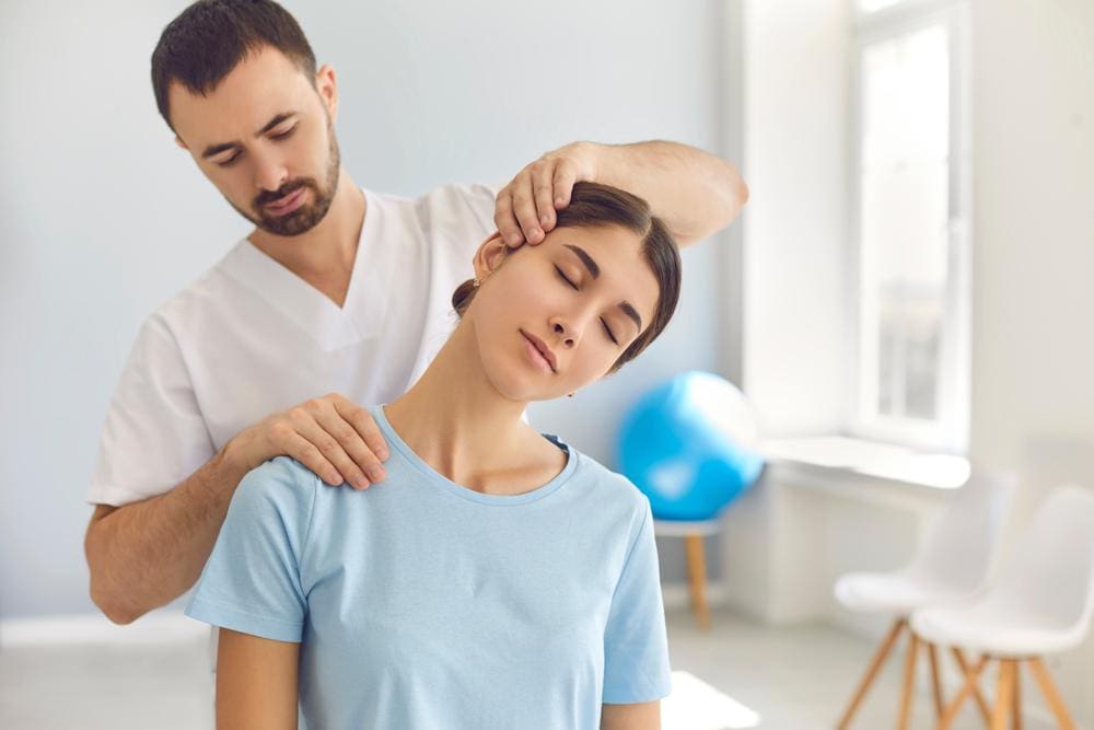 A woman is getting a chiropractic adjustment to treat her neck injury after a car accident.