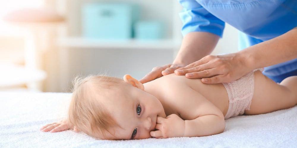 A baby is laying on his stomach and getting a gentle chiropractic adjustments.