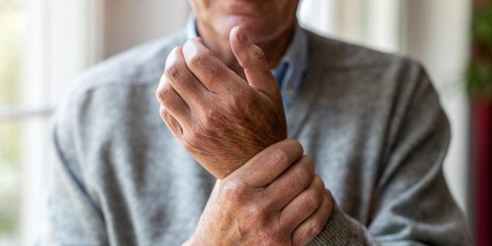 a man is suffering from degenerative arthritis pain in his wrists.