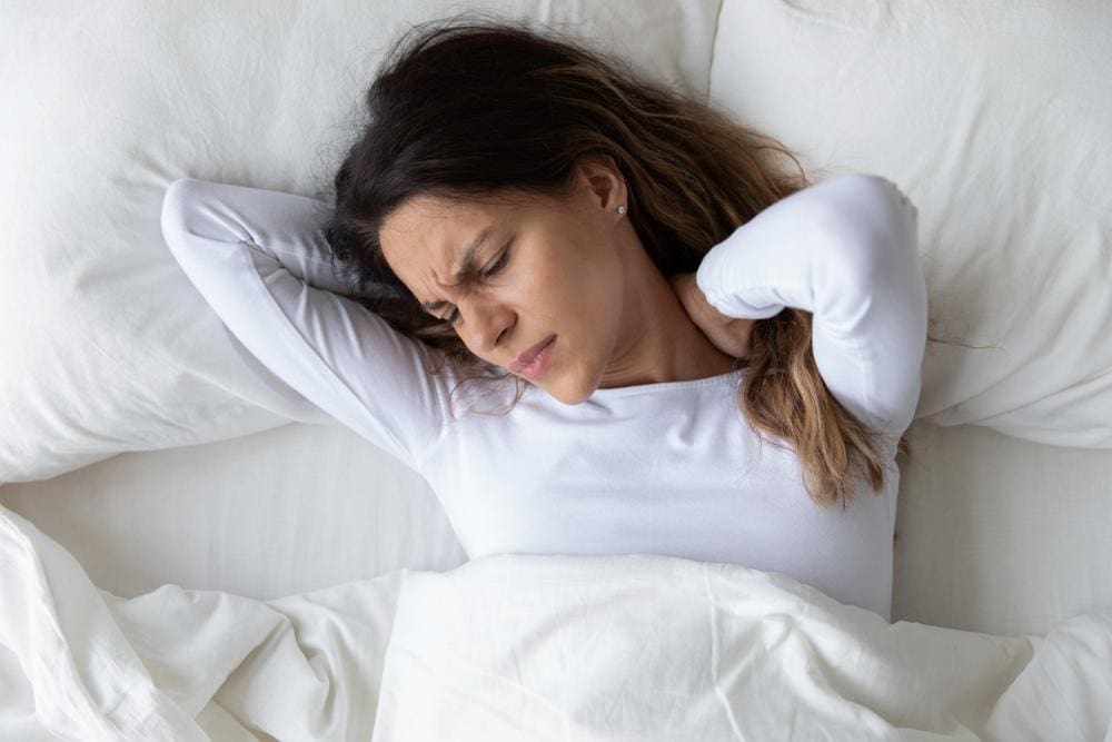 A young woman cannot sleep because of pain caused by a herniated disc in her neck.