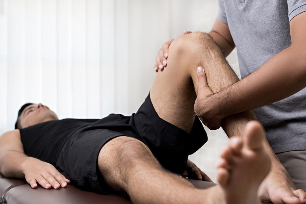 A man is getting a chiropractic adjustment to alleviate pain from knee arthritis. 