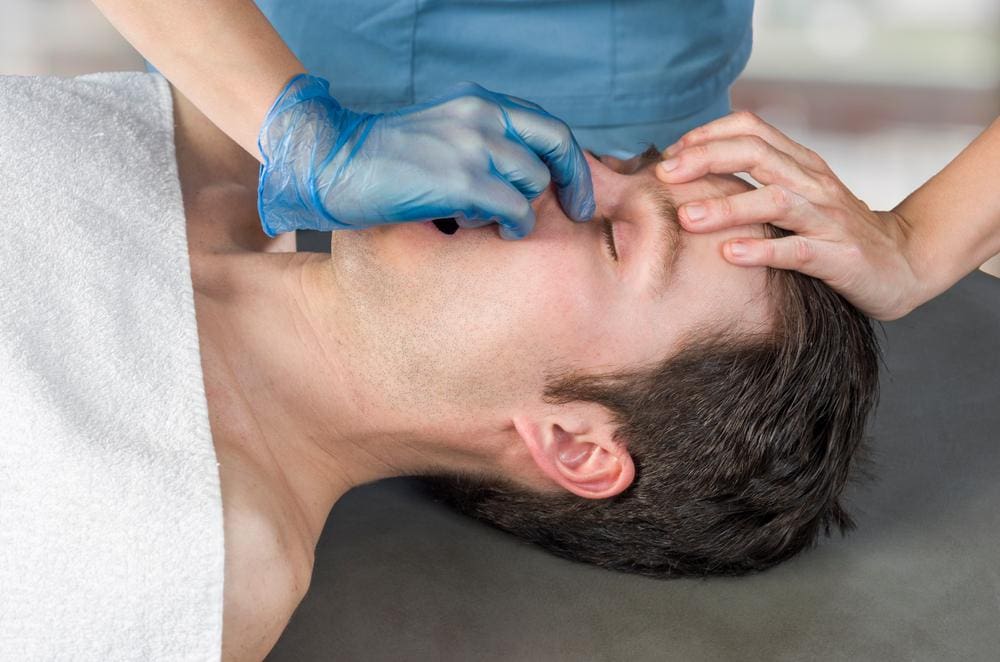 A man is getting a sinus adjustment and sinus massage from a chiropractor. 