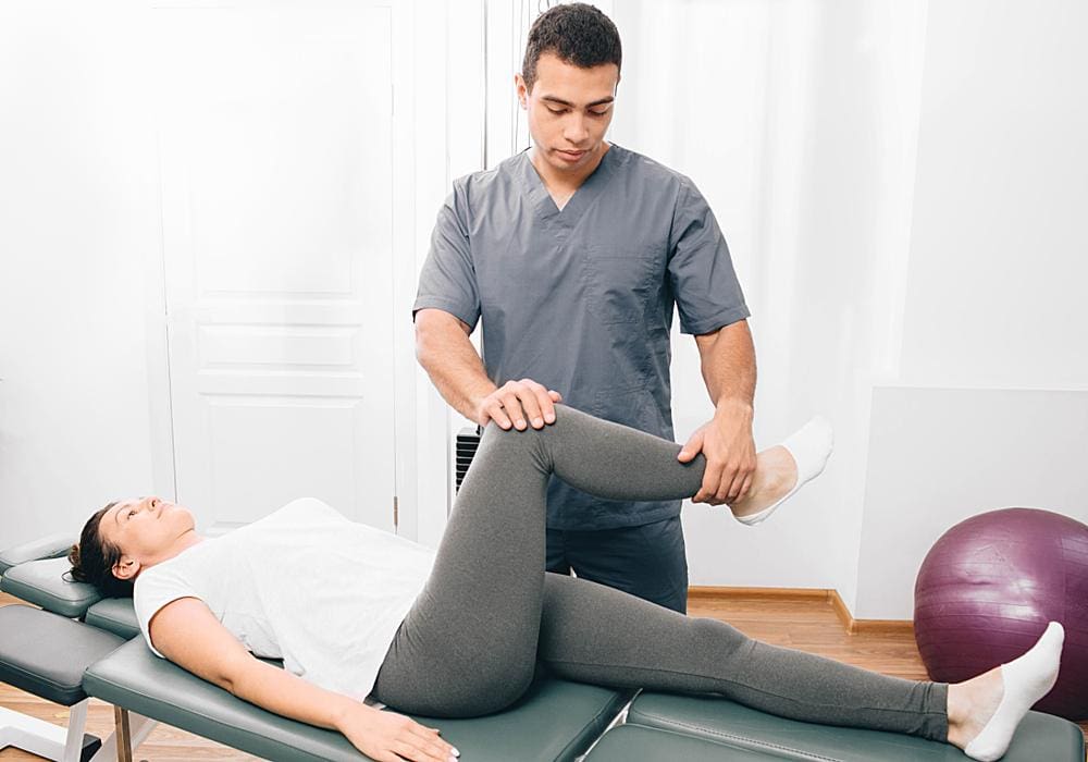 A chiropractor is performing chiropractic adjustments on a female patient to treat her hip dysplasia.
