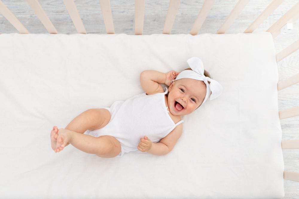 A baby is laying in a crib and smiling. 