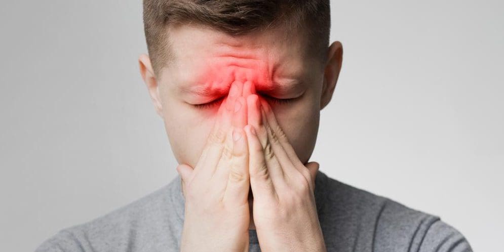 A man is holding his nose because his sinuses are inflamed.