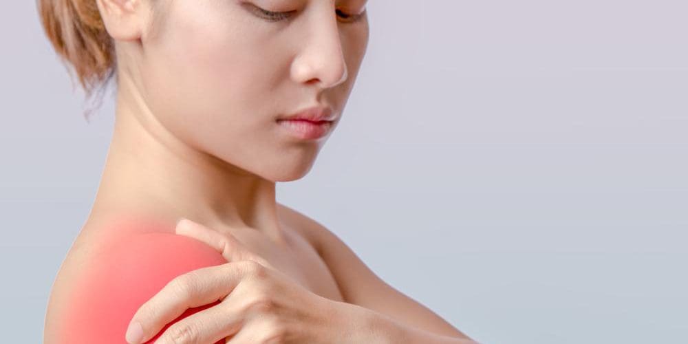 A woman is holding her shoulder because of pain from a soft tissue unjury.