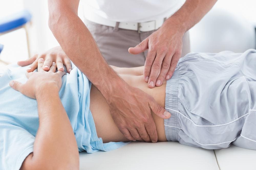 A Chiropractor is palpating and examining abdomen of patient with kidney pain. 