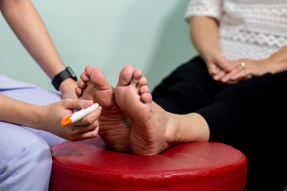 A chiropractor is examining a woman's feet who has neuropathy pain. 
