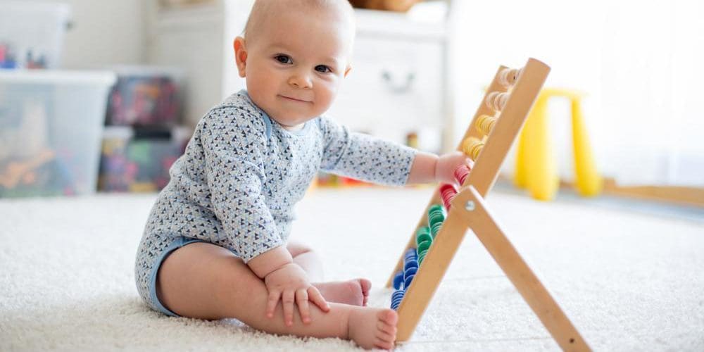 a happy baby is sitting on the floor playing with his toys.