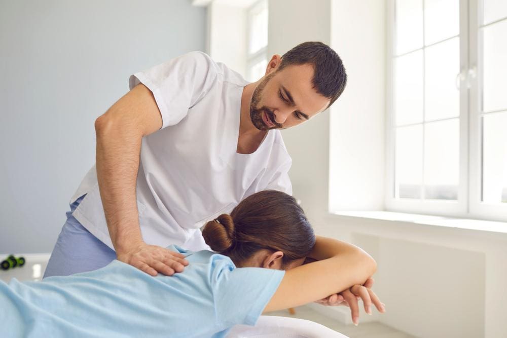 A woman is getting a spinal adjustment from a chiropractor to ease her fibromyalgia symptoms.