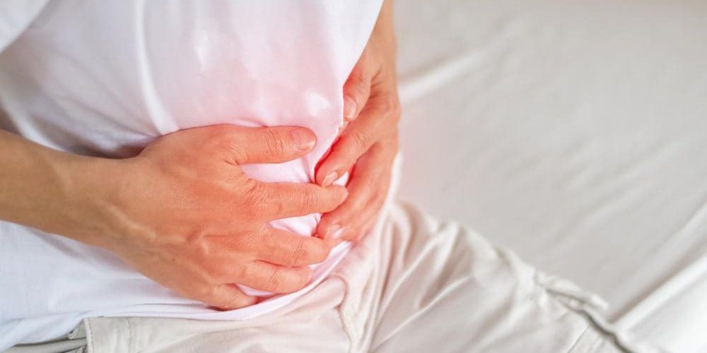 a man is holding his stomach because of pain from a hiatal hernia