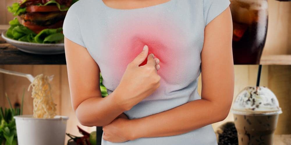A woman is touching her chest while suffering from acid reflux.