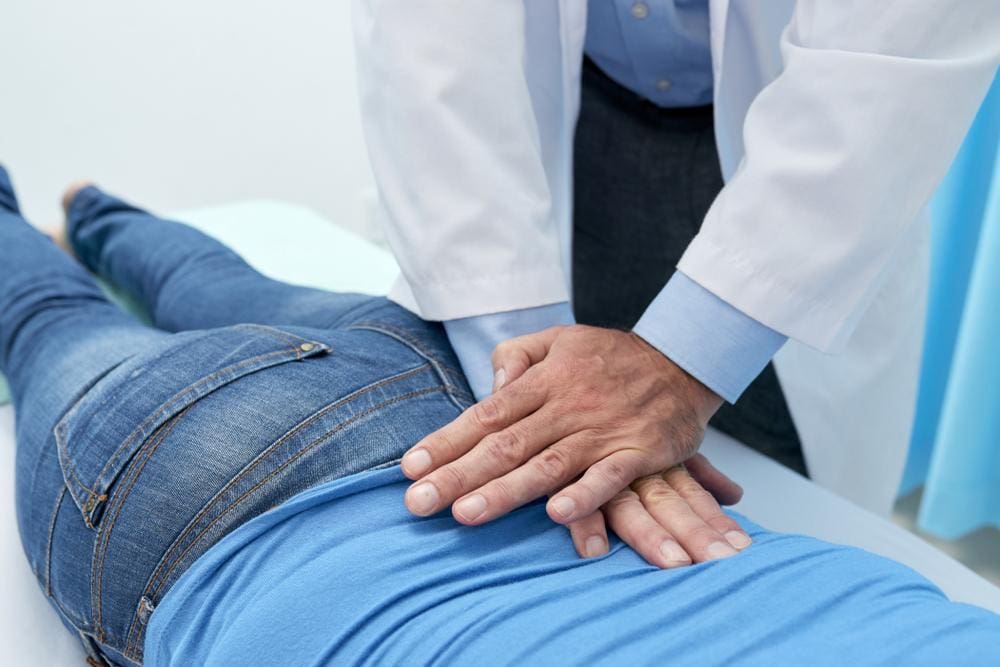 Chiropractor adjusting back of female patient.