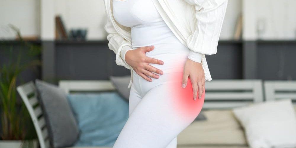 A woman is slightly hunched and holding her hip because of pain from hip arthritis.