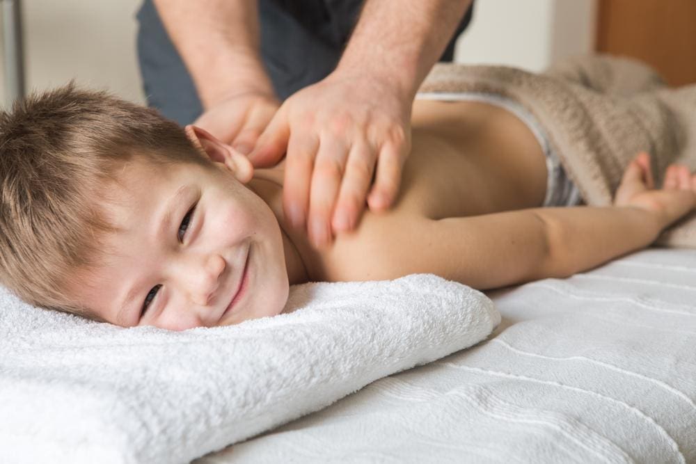 Young boy smiling while getting back massage.
